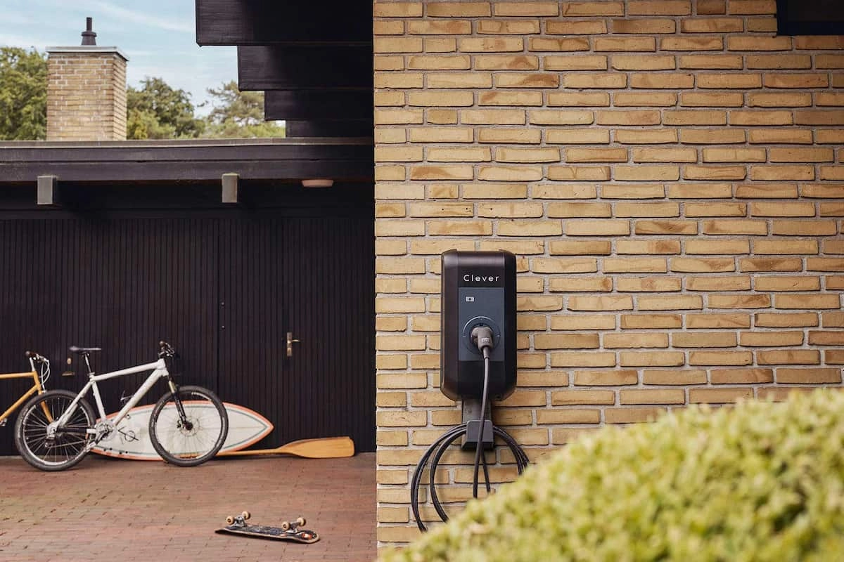 Clevers ladeboks i sort hænger på en gul murstensvæg. Man kan se en cykel og et surfbræt i baggrunden.