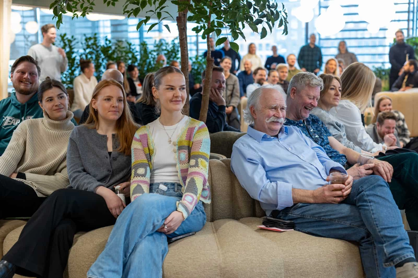 Mennesker sidder i sofa under en plante