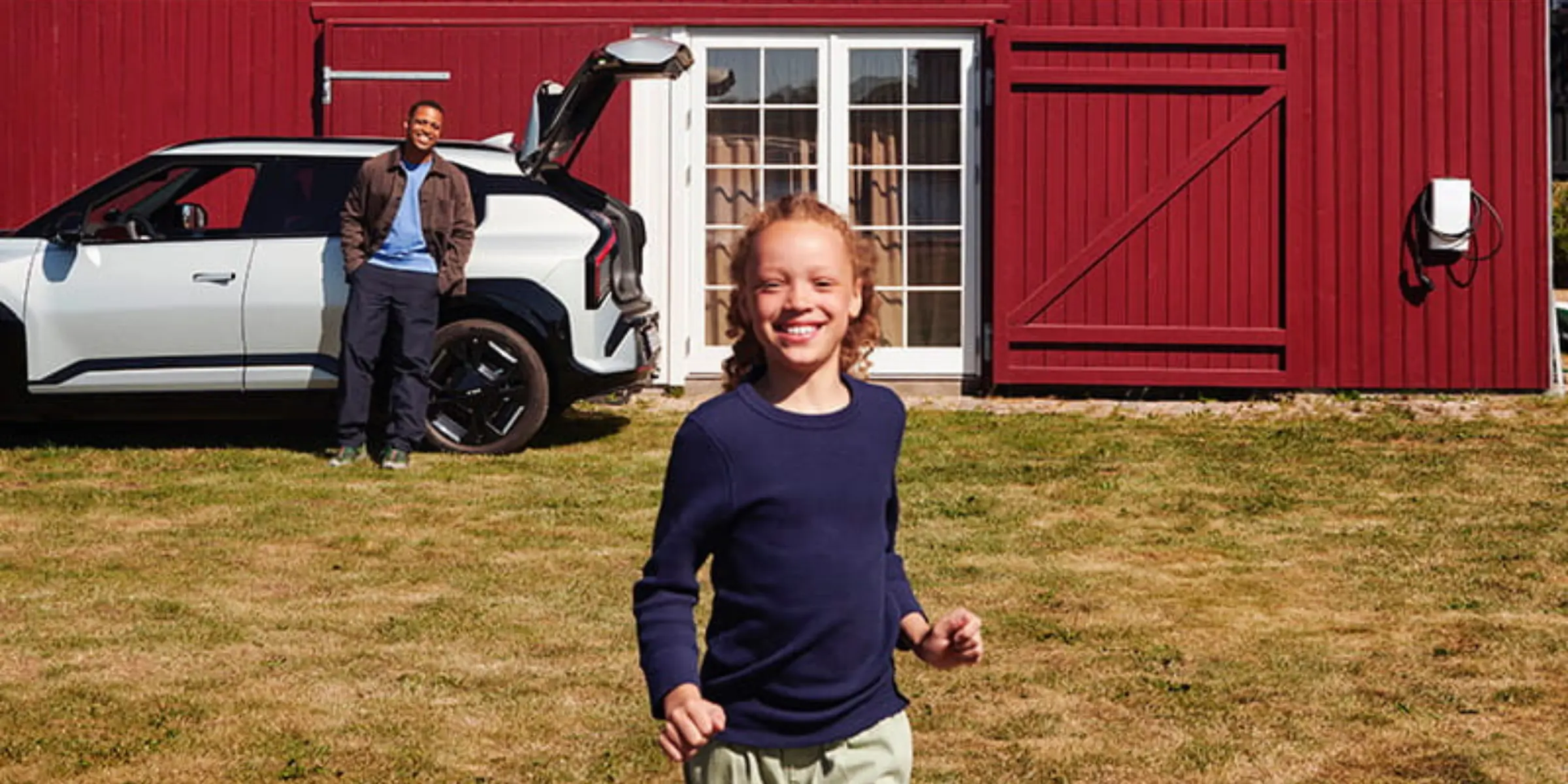 Clever ladeboks på rødt sommerhus med barn der løber foran